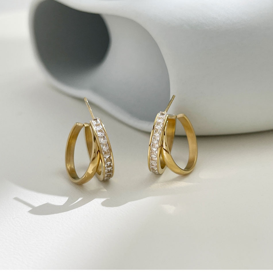 Vergoldete Creolen mit Zirkonia-Steinen auf heller Oberfläche – eleganter Alltags-Ohrring