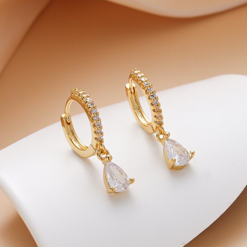 Small Drop White - Entdecke den lässigen Charme unserer vergoldeten Small Drop Creolen! Diese kleinen Schmuckstücke sind echte Hingucker, mit funkelnden Zirkonia-Steinchen und einem niedlichen Wassertropfen-Anhänger