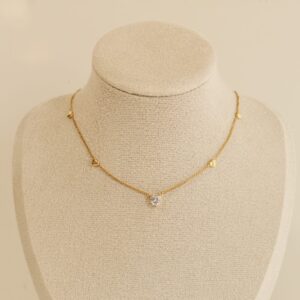 Vergoldete Herz Kette mit zentralem Zirkonia-Stein und kleinen Herzanhängern auf beiger Schmuckbüste