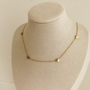 Vergoldete Herz Kette mit kleinen matten Herzanhängern auf beigefarbener Schmuckbüste – minimalistisches Design
