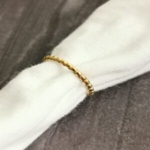 Vergoldeter Loop Ring auf weißem Stoff – filigranes Gliedermuster im minimalistischen Design