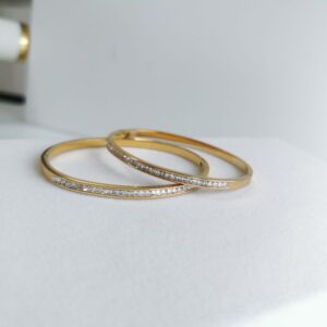 Zwei vergoldete Armreifen mit Zirkonia auf weißem Untergrund – funkelndes Schmuckset in klassischem Design